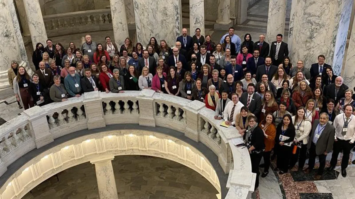 A group of people circle around the Idaho State Capitol rotunda. 