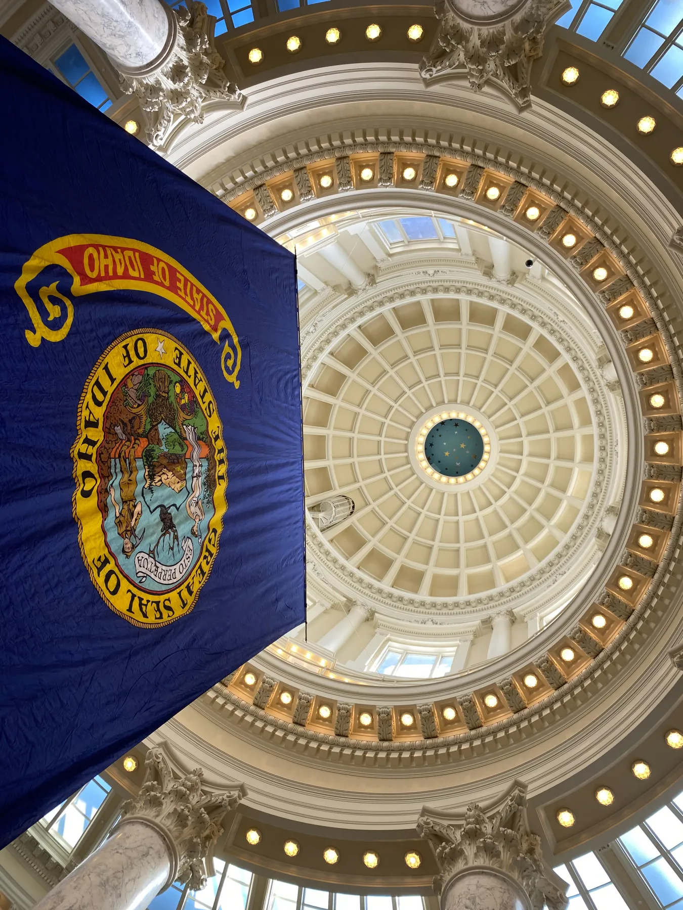 A view looking up at the Idaho Statehouse rotunda with the Idaho flag