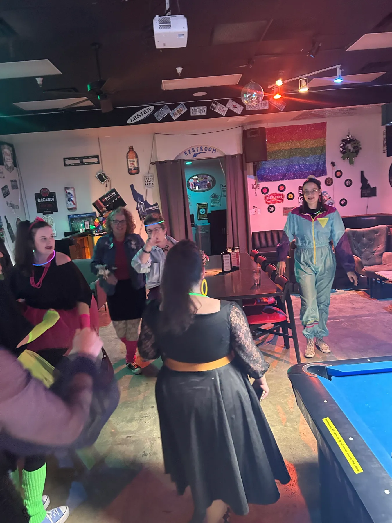 People gather in a bar in 1980s prom gear. 