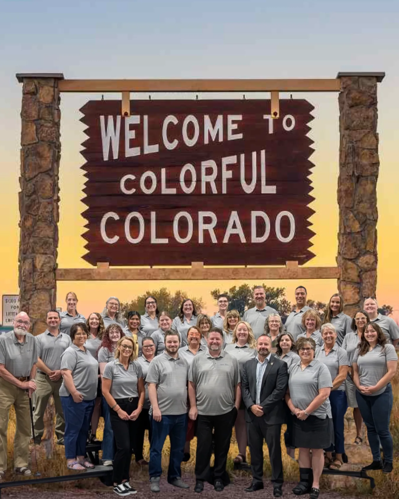 A group shot of people in gray shirts in front of a sign that says Welcome to Colorful Colorado