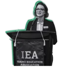 A woman stands at a podium with an IEA banner.