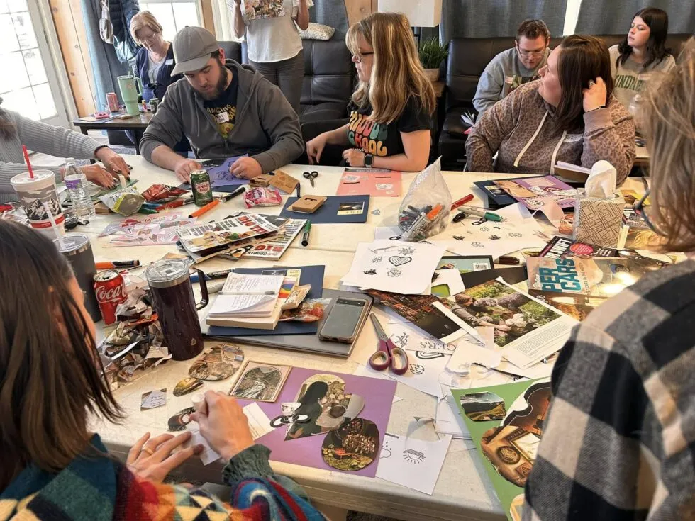 A group of people gathered around a table full of magazines and doing crafts