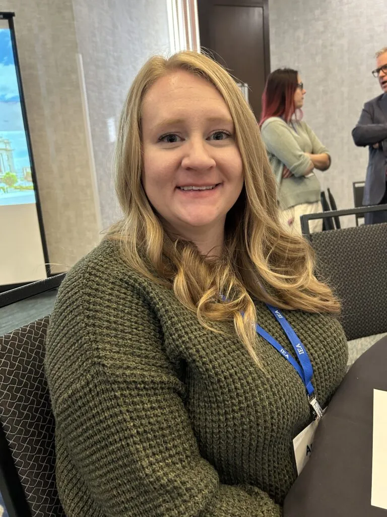 A woman in a green sweater smiles at the camera