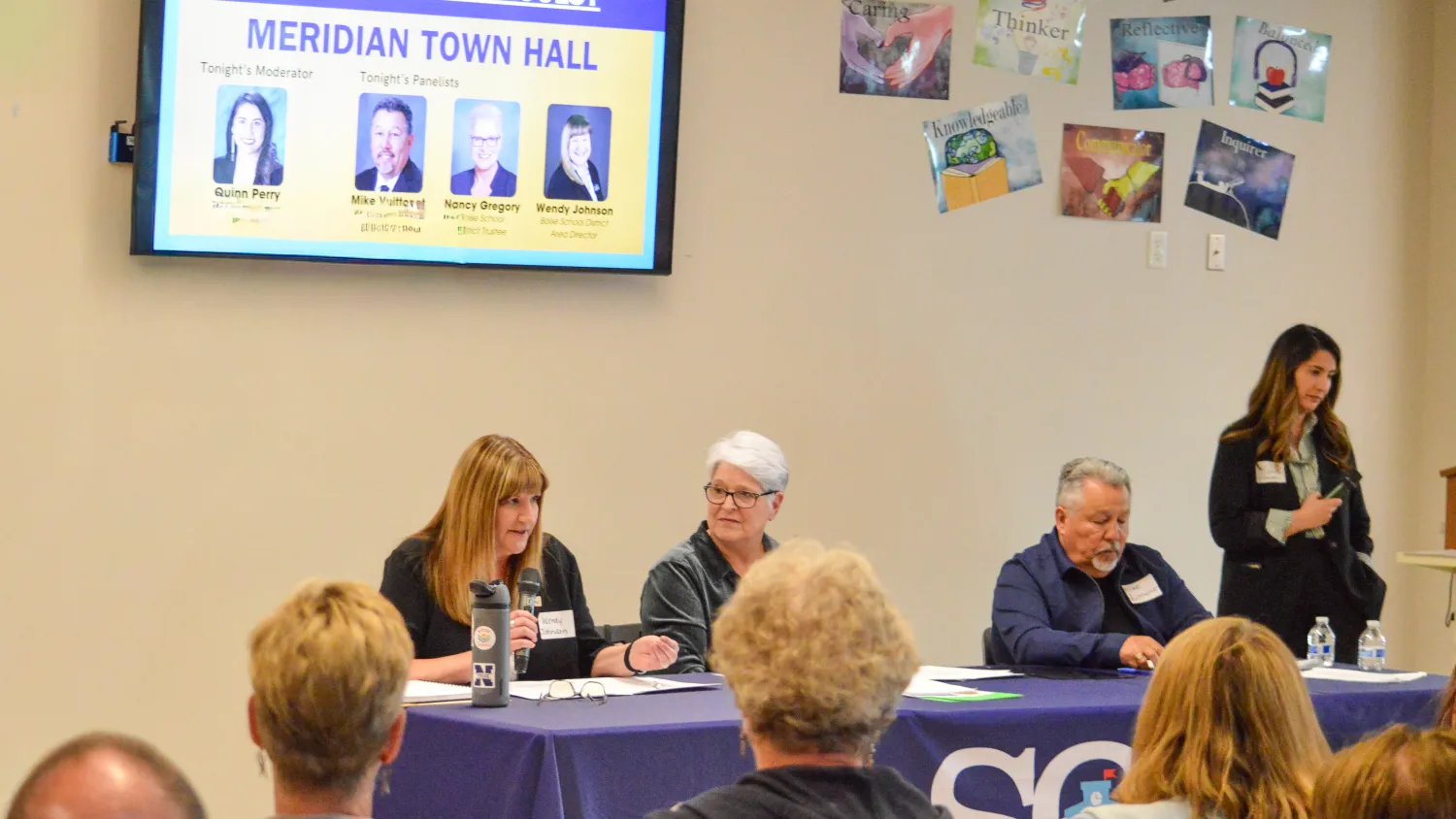 Crowd listens to panel at a Meridian Town Hall.