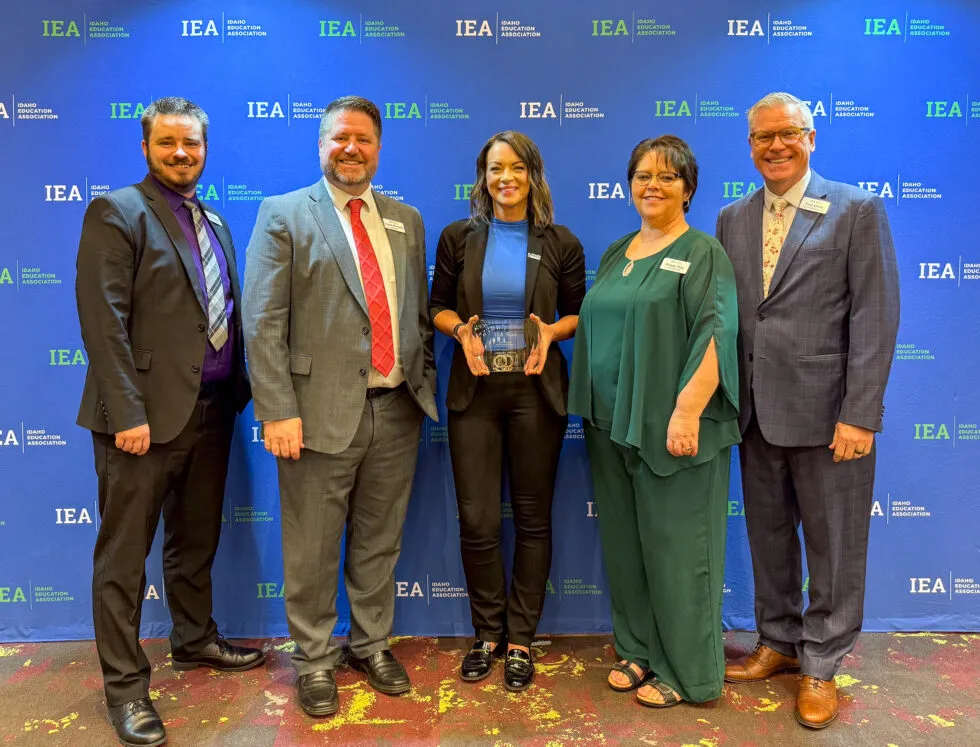 A group of people pose with a woman holding an award
