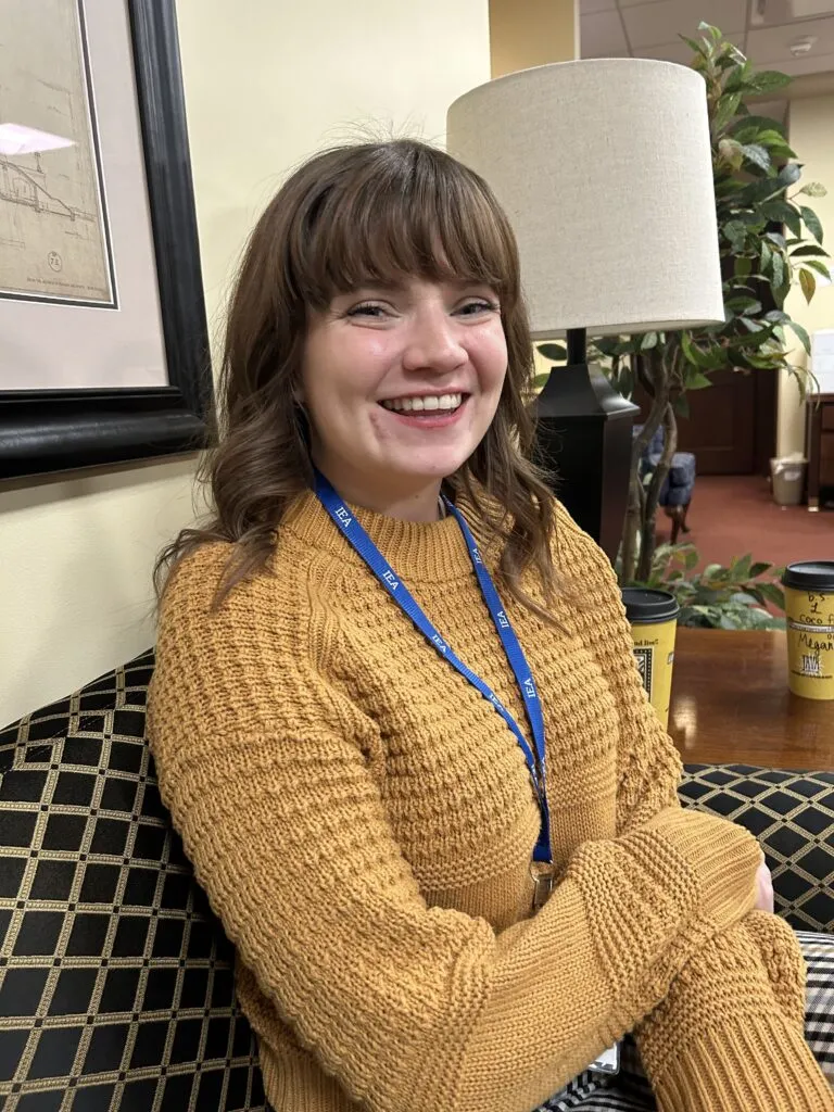 A woman in a yellow sweater smiles at the camera