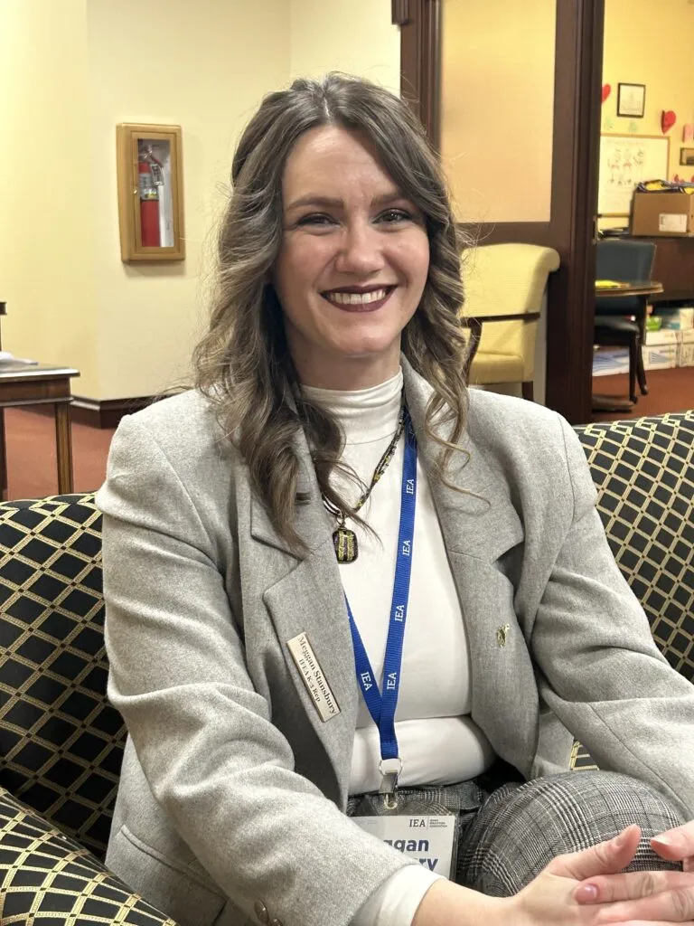 A woman wearing a gray suit smiles at the camera
