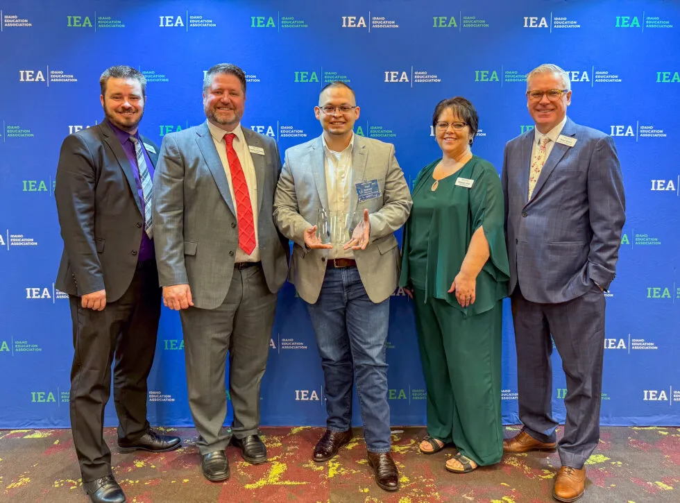 A group of people poses with a man holding an award