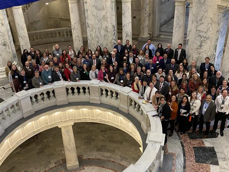 A group of people circle around the Idaho State Capitol rotunda. 