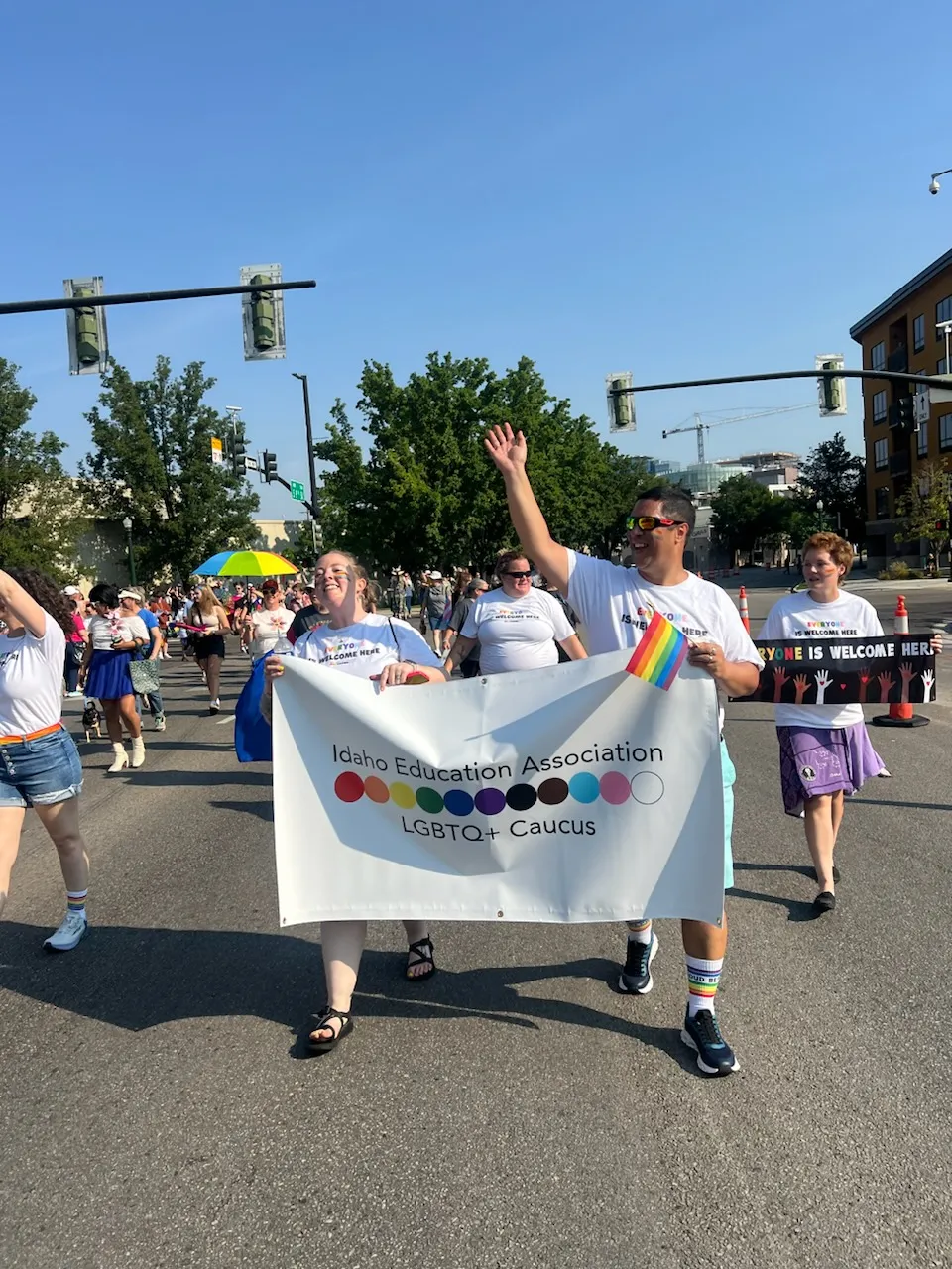 Members of the IEA LGBTQ+ Caucus hold a sign and walk in the Boise Pride Parade