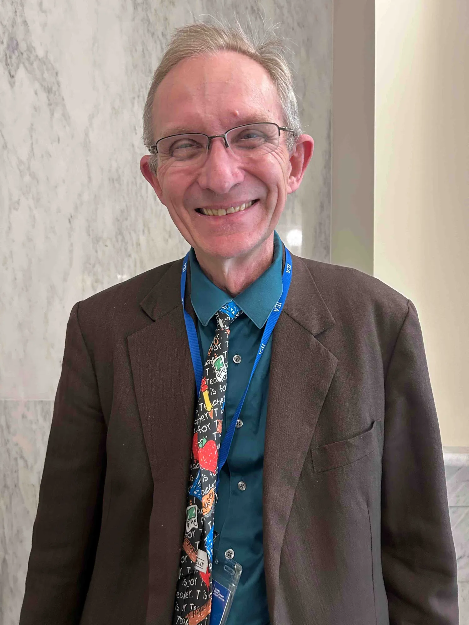 A photo of a man in a suit and tie smiling at the camera