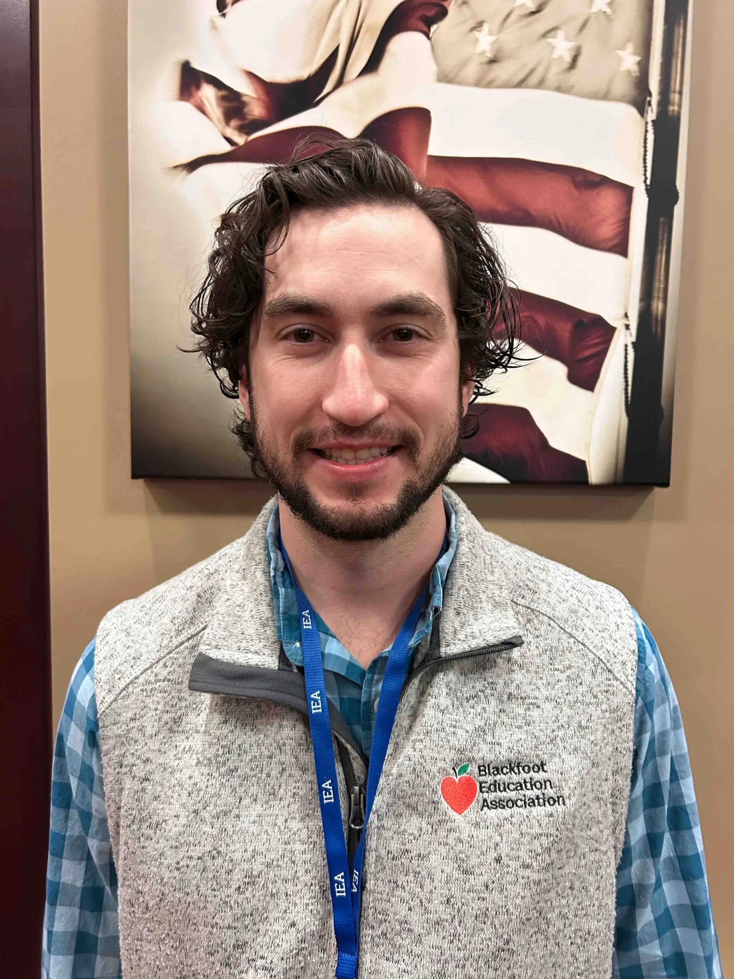 A photo of a man in a vest smiling at the camera