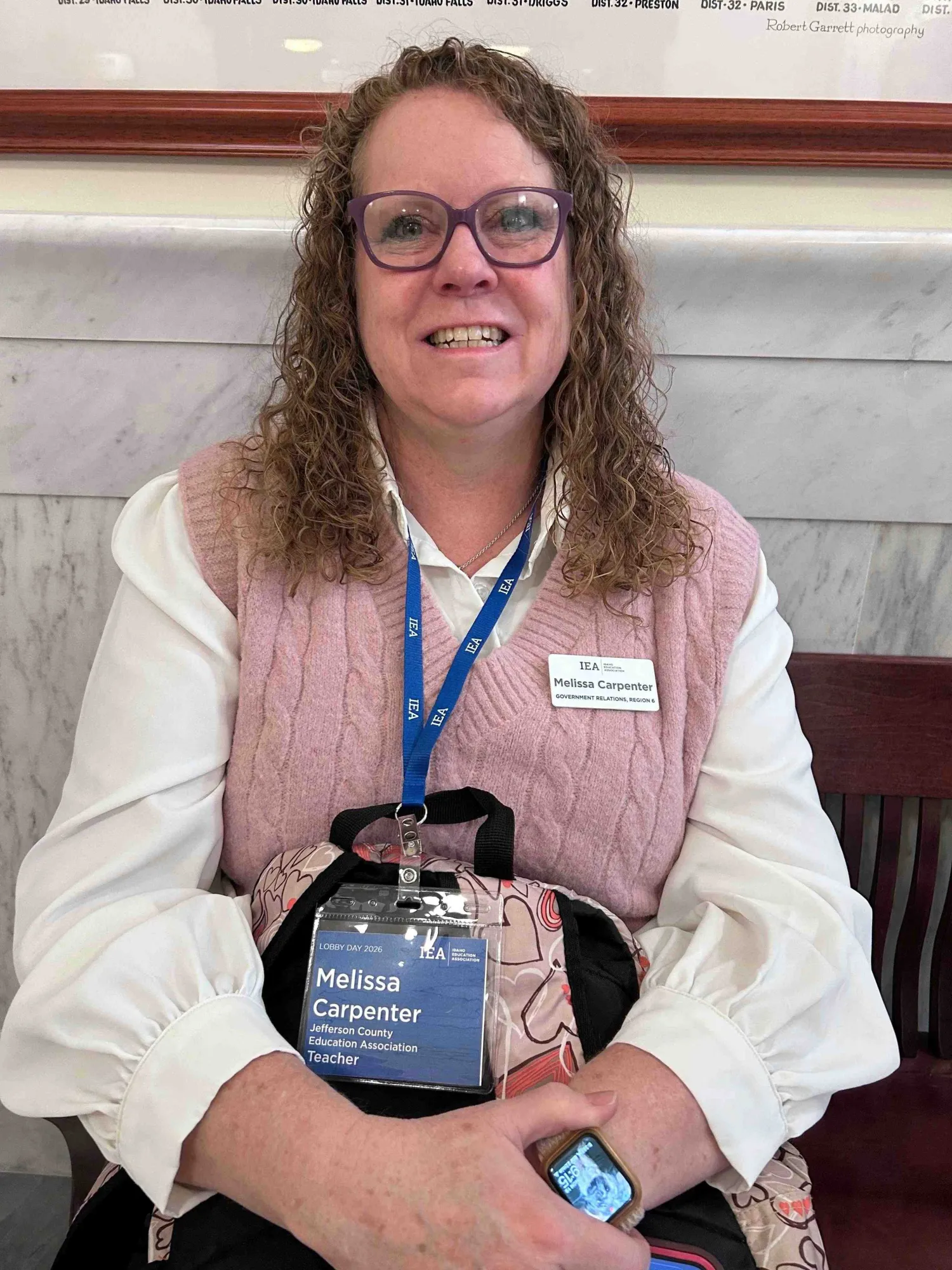 A woman in a white shirt and pink vest smiling at the camera