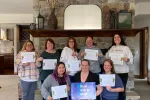A group of people stand in front of a fireplace and hold certificates