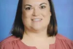 A school portrait of a woman with brown hair wearing a rose-colored shirt