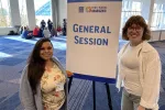 Two women flank a sign that says General Session