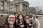 A group of college students poses in front of the Idaho Statehouse