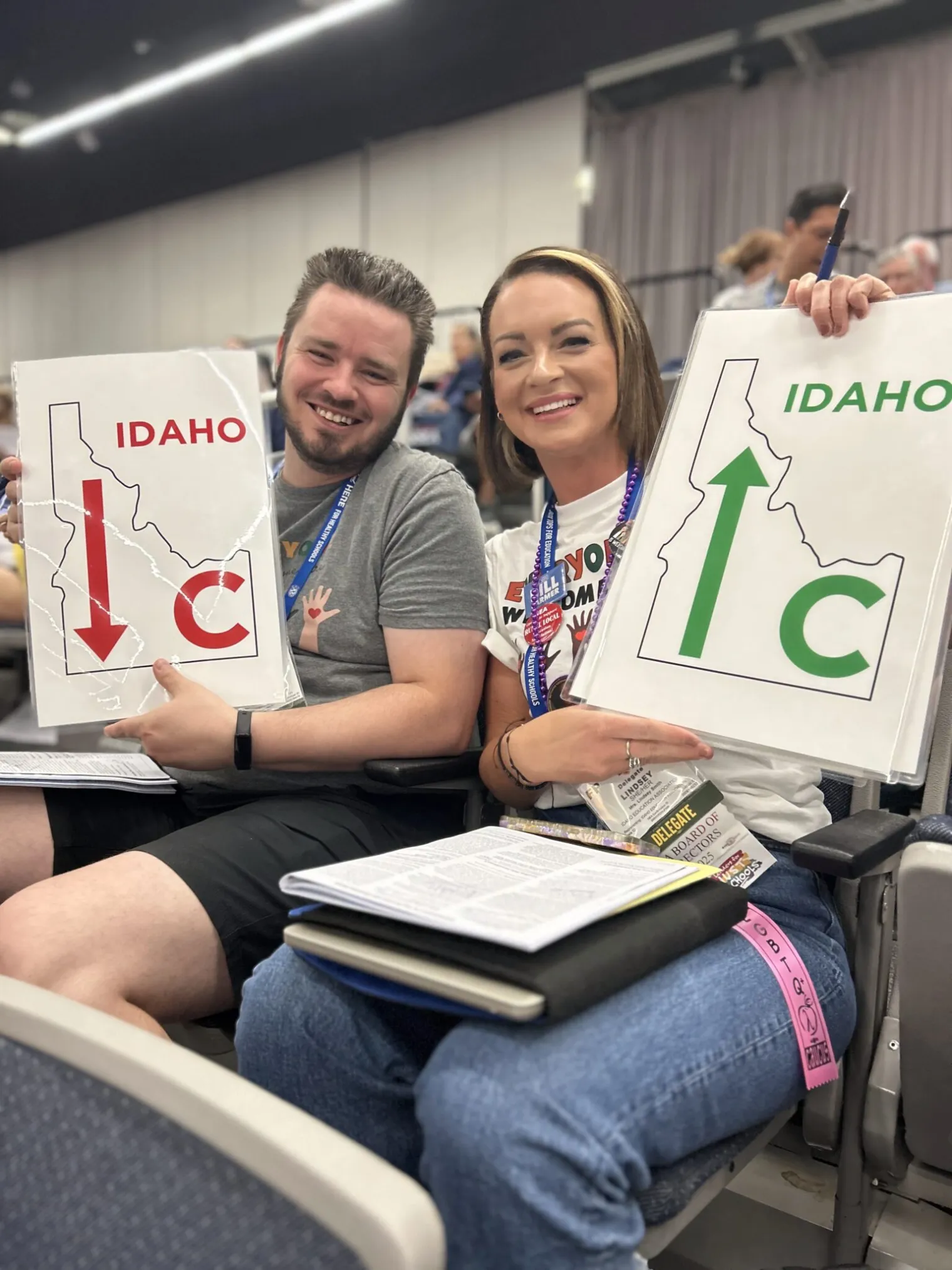 A man and a woman hold up signs