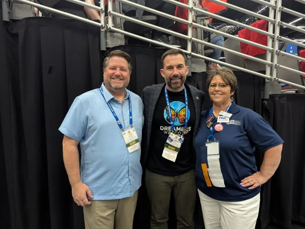 Two men and a woman smile at the camera