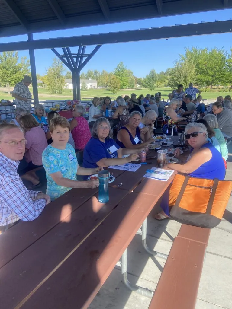 Retired union members eating around a table in a park on a sunny day
