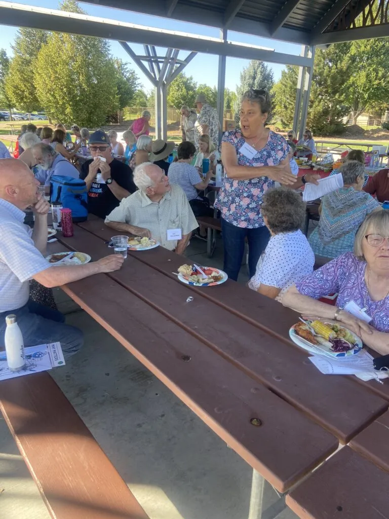 Retired members talk around a picnic table