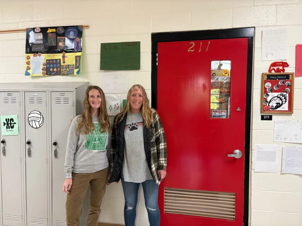 Two women in zombie makeup pose in a school hallway