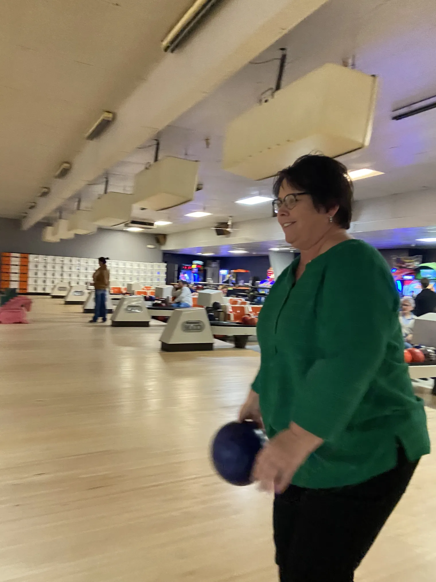 A woman wearing a green shirt bowls