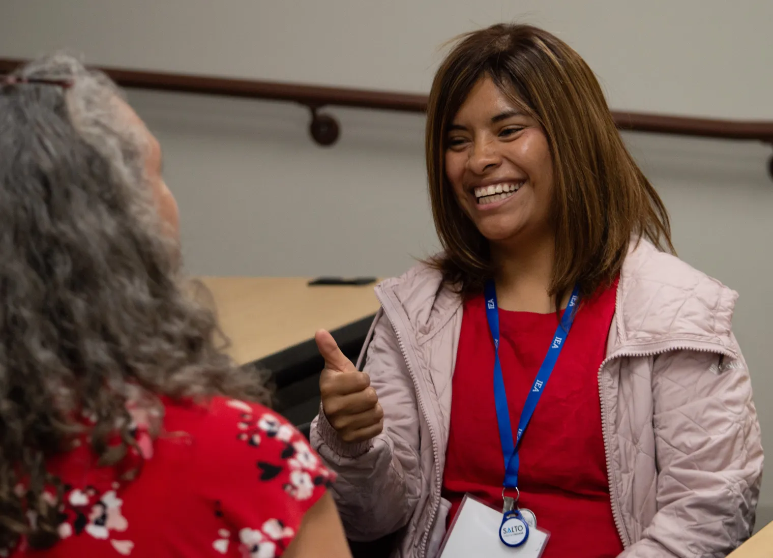 A woman smiles while praciticing American Sign Language