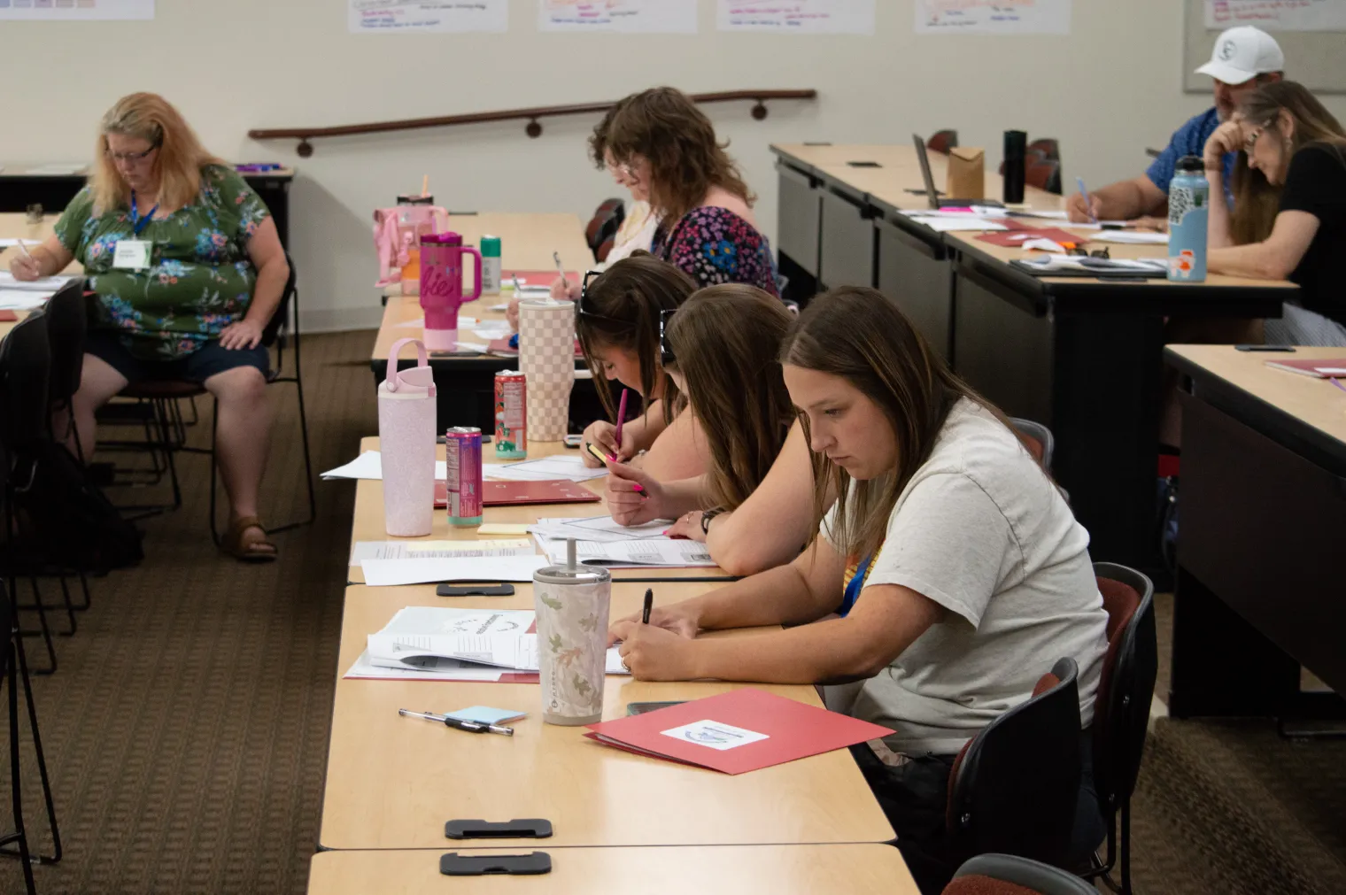 A group of three women sit at a table and work on their project