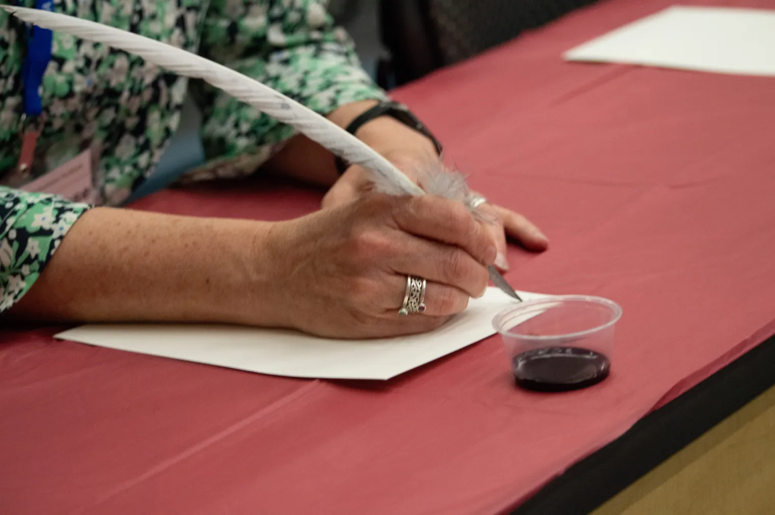 A detail shot of a woman using a quill and ink