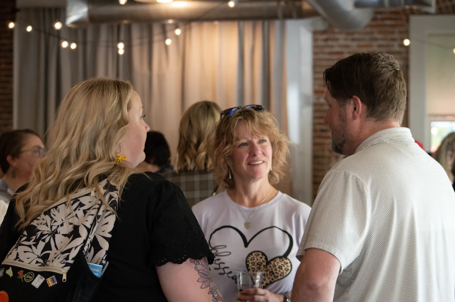 Two women and a man speak in a party setting