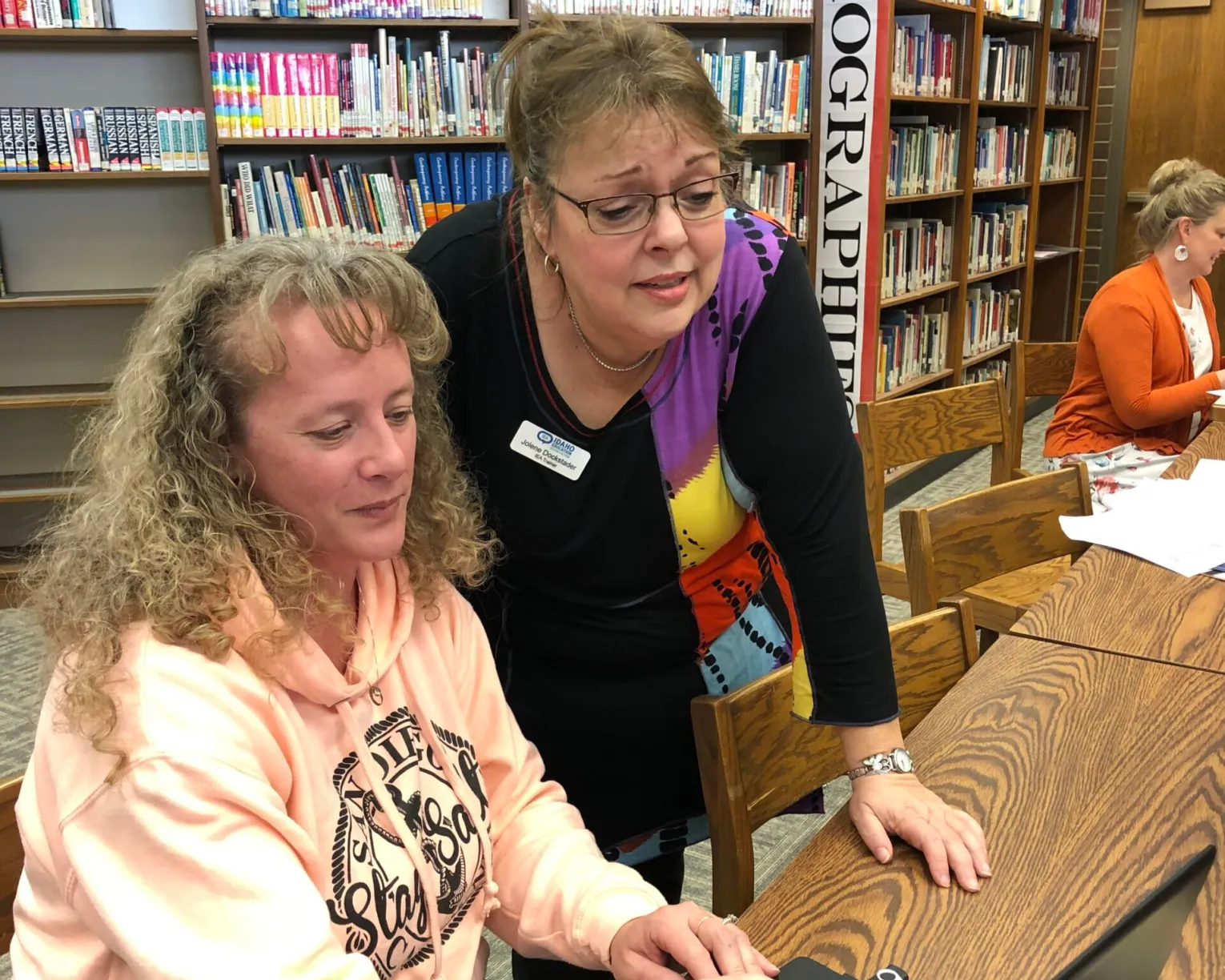 Two women looking at a computer screen in a library, one is mentoring the other