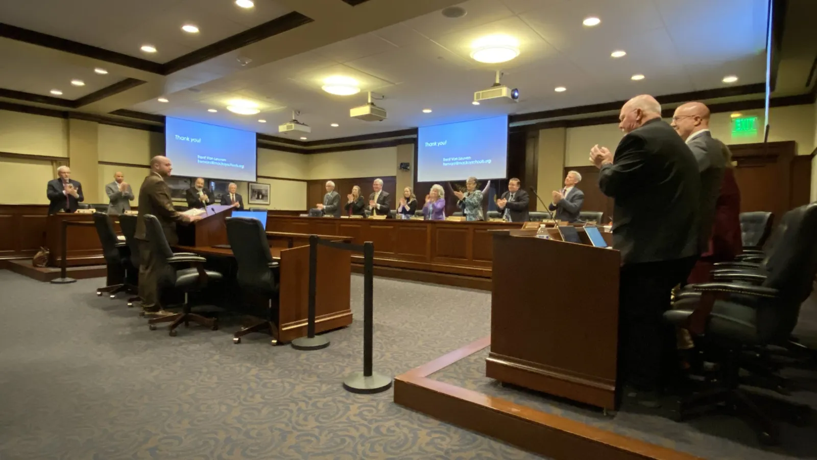 A man receives a standing ovation from lawmakers in a committee room