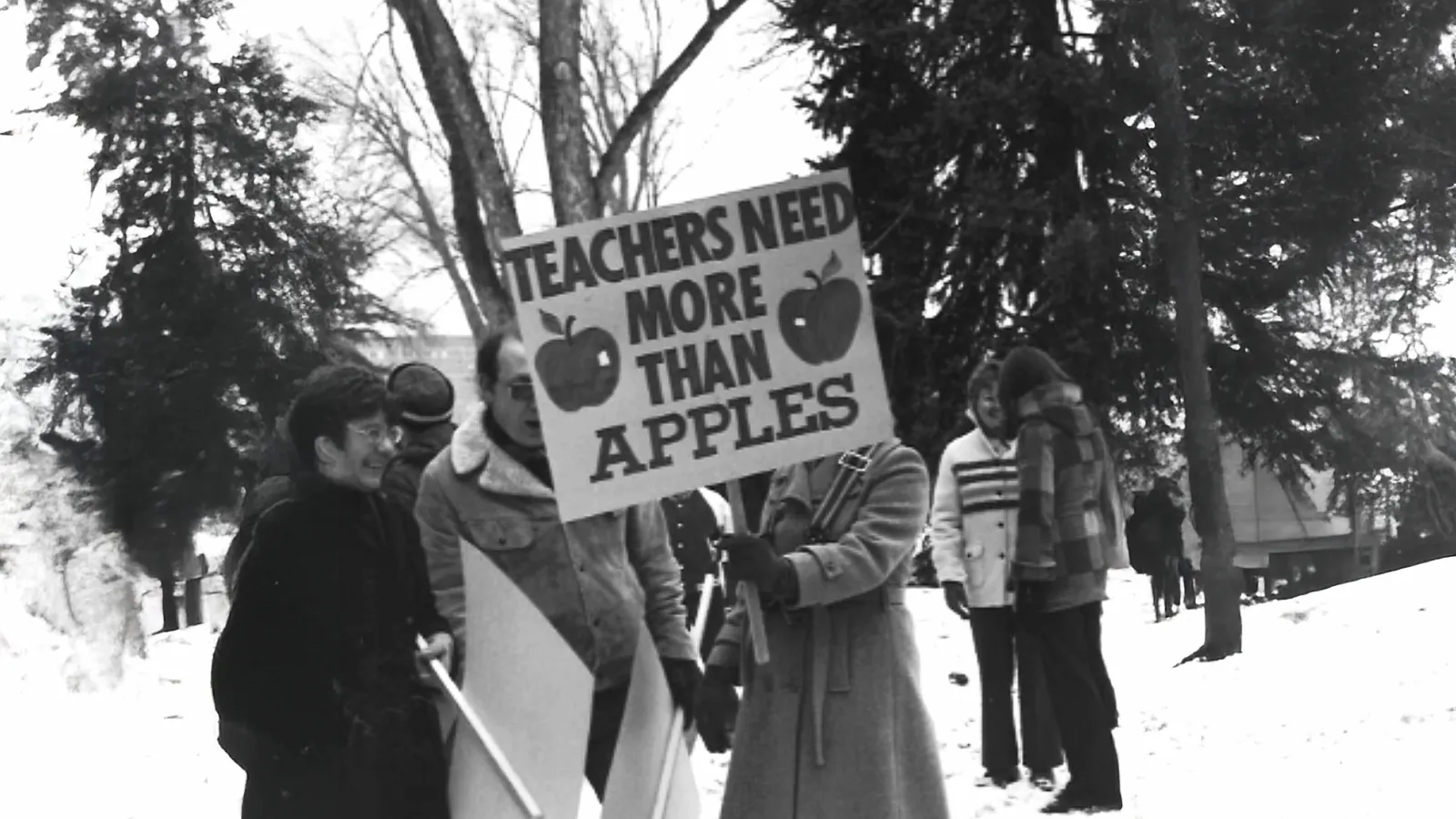 1970s IEA protest with a sign that reads "Teachers need more than apples."