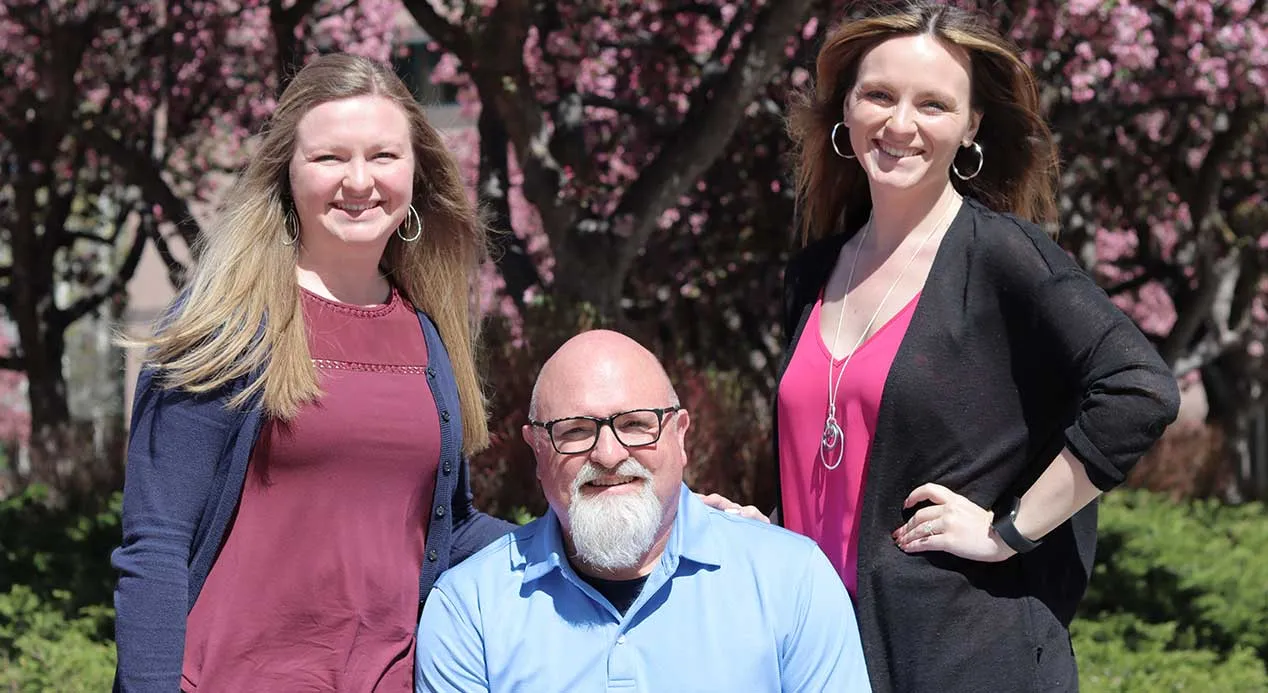 A seated man is surrounded by two young women