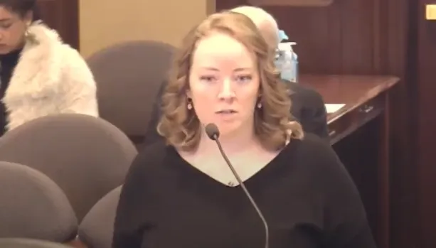A woman in a black shirt testifies before a committee