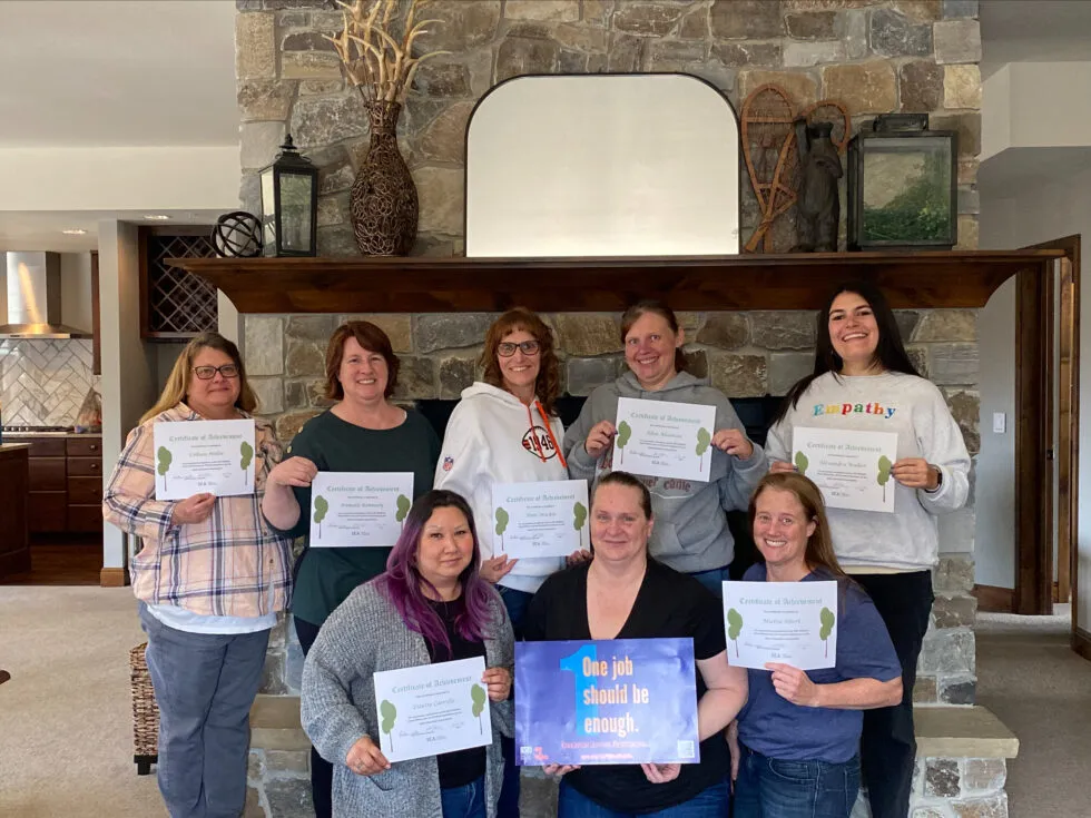 A group of people stand in front of a fireplace and hold certificates