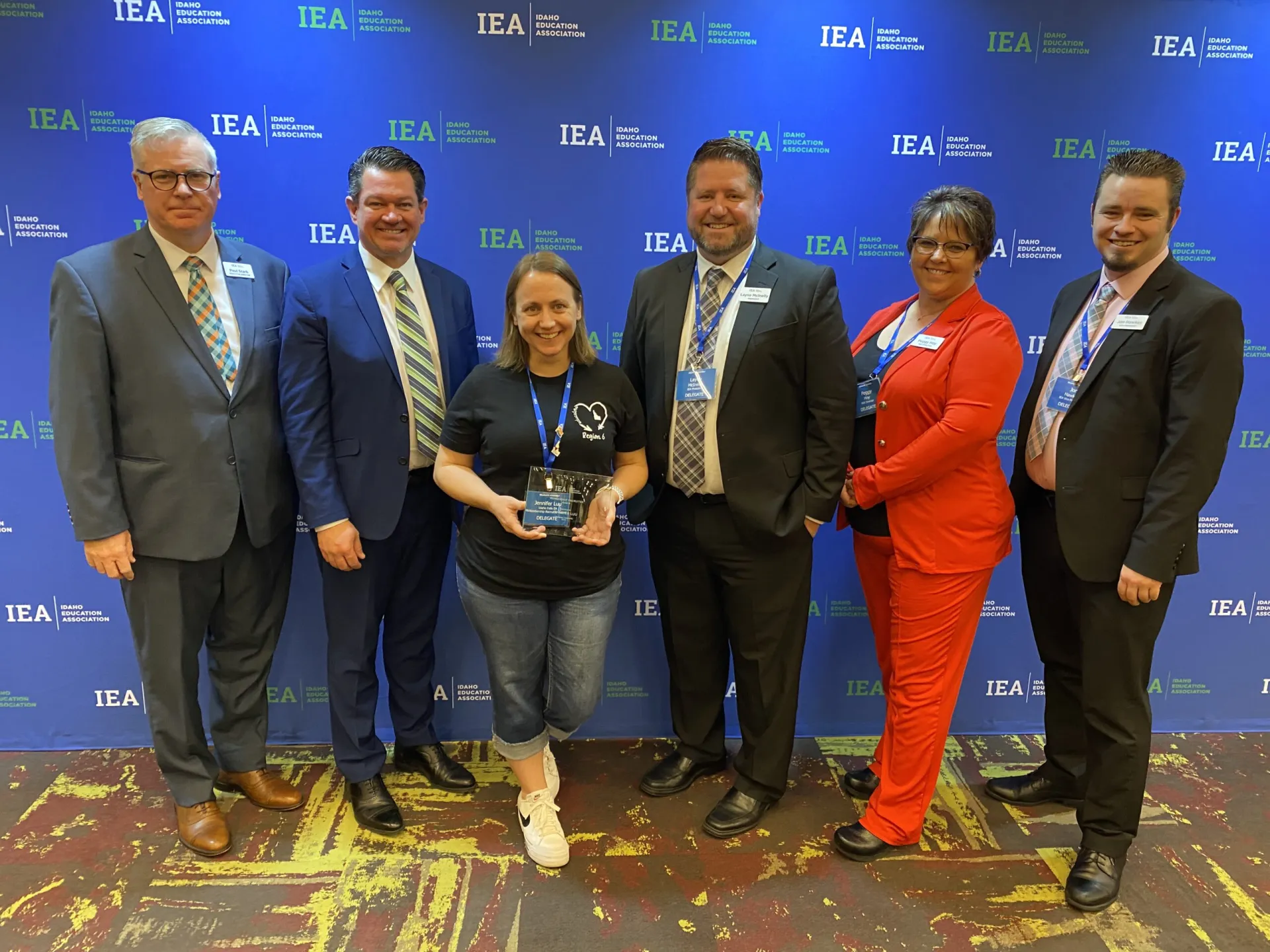 A woman wearing a black shirt and jeans accepts an award