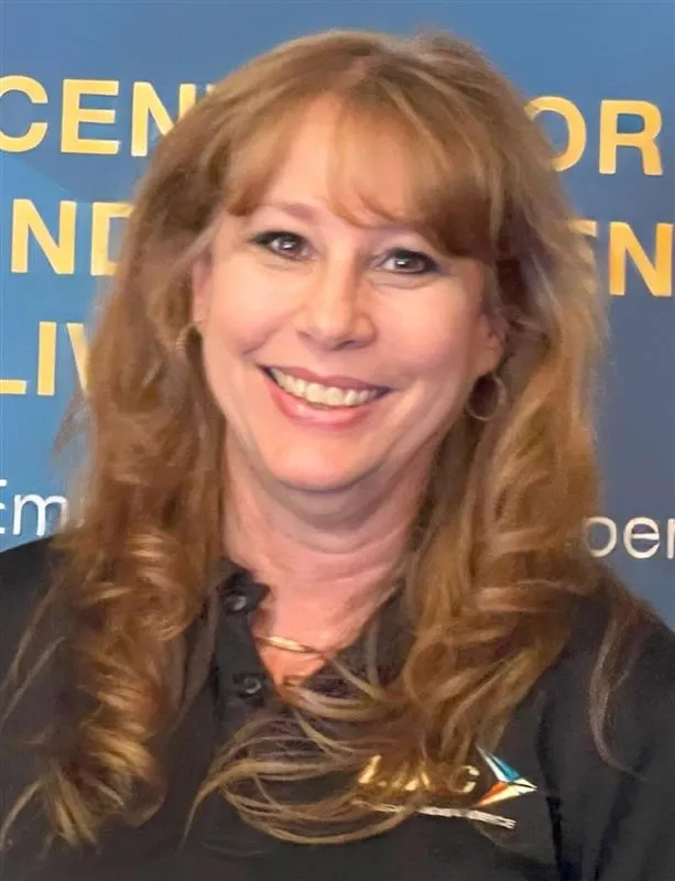 A woman in a black shirt smiles at the camera