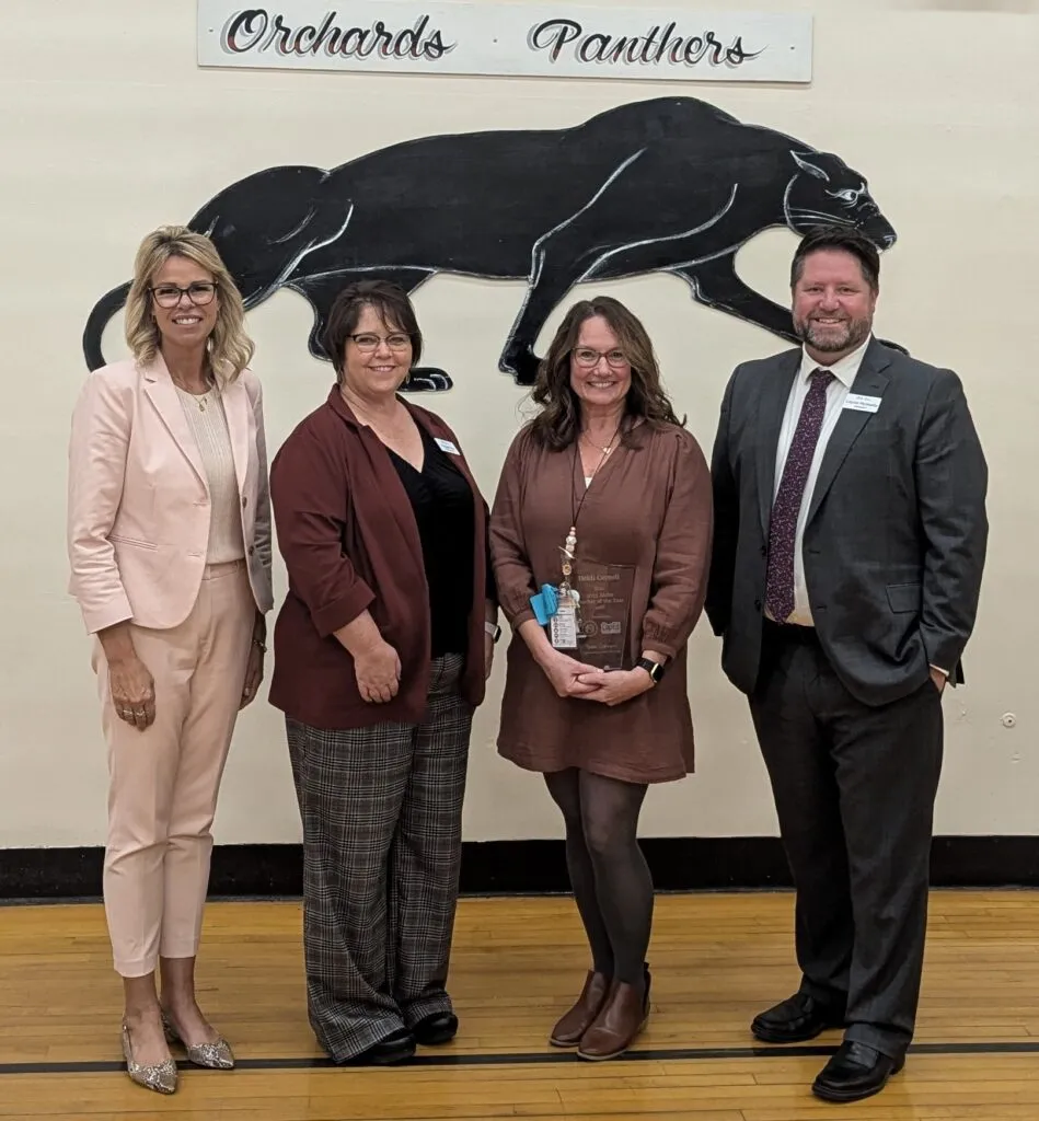 A group of people pose in front of an Orchards Panthers sign