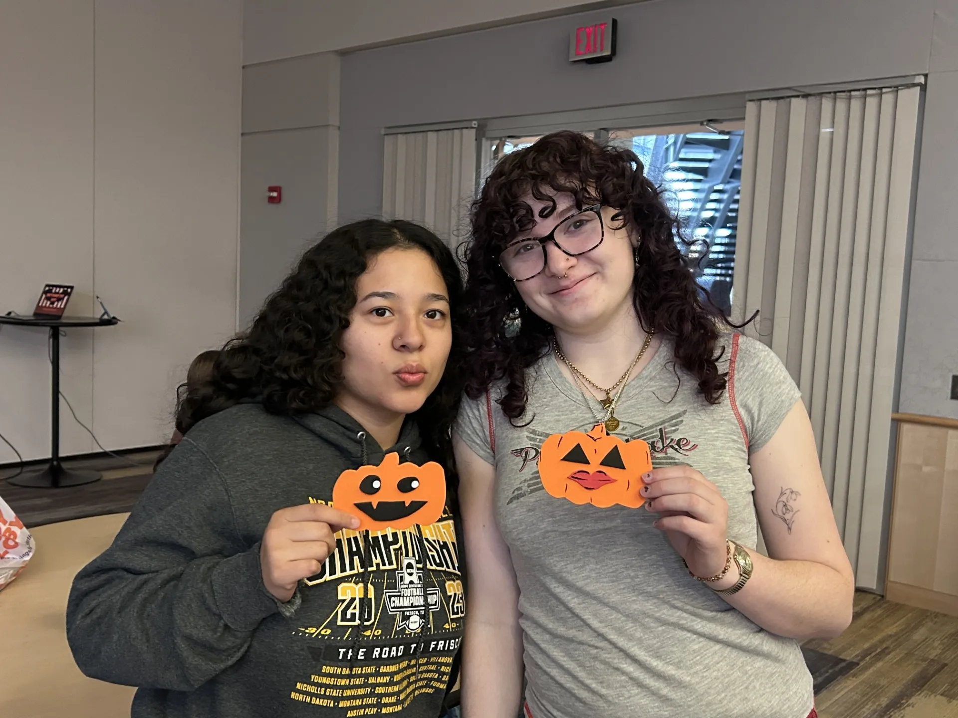 Two women hold paper jack-o-lanterns