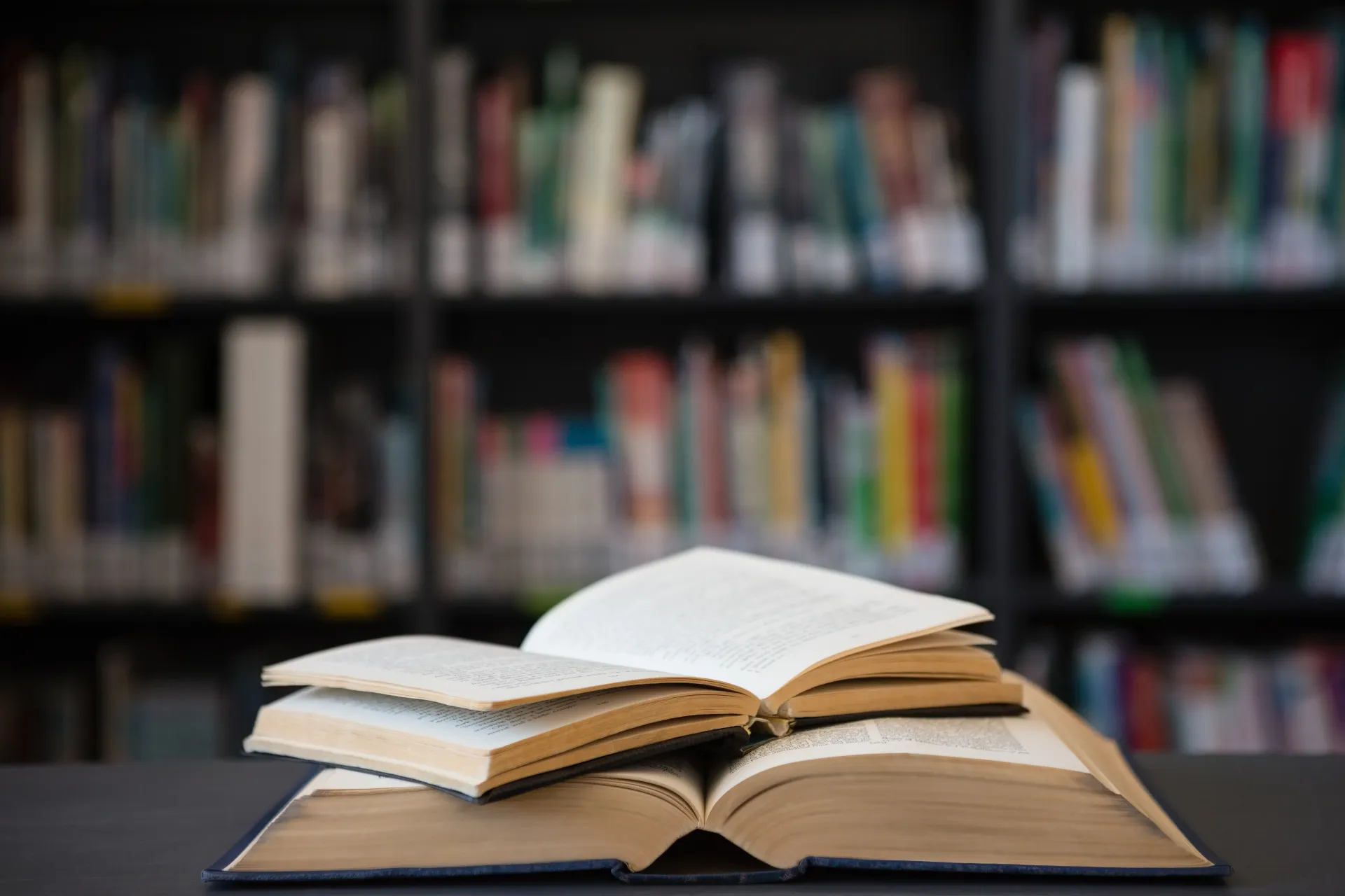 Two books on a table with bookshelves behind them