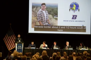A person at a podium speaks in front of a group