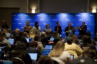 A group of people stand in front of a packed conference hall