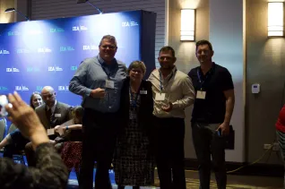 Three men and a woman take a group photo