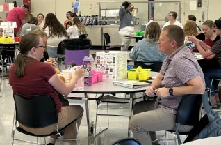 Two people sit at a round table in a cafeteria and talk
