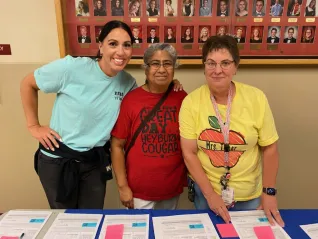 Three women prepare handouts