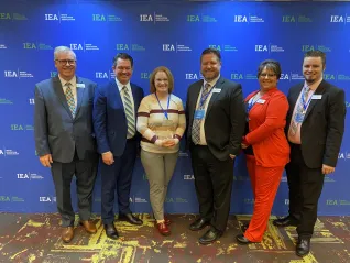 A woman holds an award and is flanked by IEA leadership