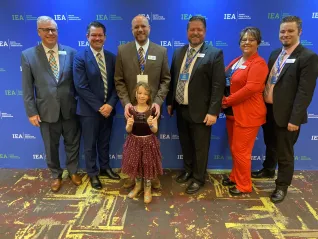 An award winner poses with IEA leadership and his young daughter