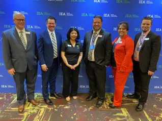 A woman wearing a black IEASO shirt poses with IEA leadership
